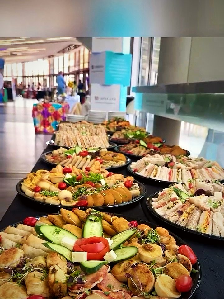 A long buffet of sandwich, pastry and salad platters