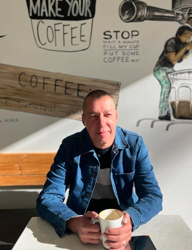 Artisan's owner at a table in the café with a cappuccino